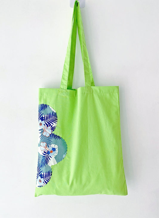 Close-up of sustainable cotton tote with handmade patchwork design, soft cotton texture visible.