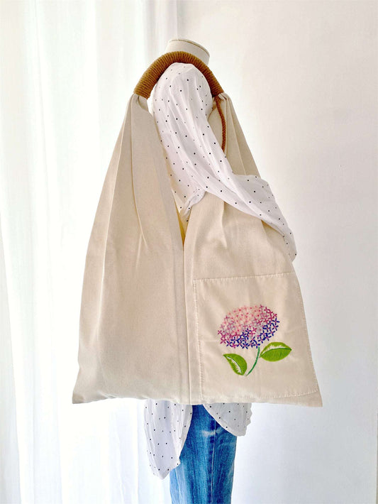 Natural fiber bag with botanical embroidery pattern