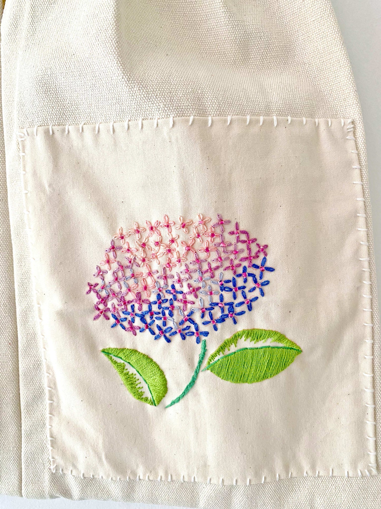 Detailed view of hand-stitched flower on canvas bag