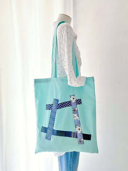 Woman strolling with a spacious cotton tote featuring unique hand-stitched patchwork for everyday ease