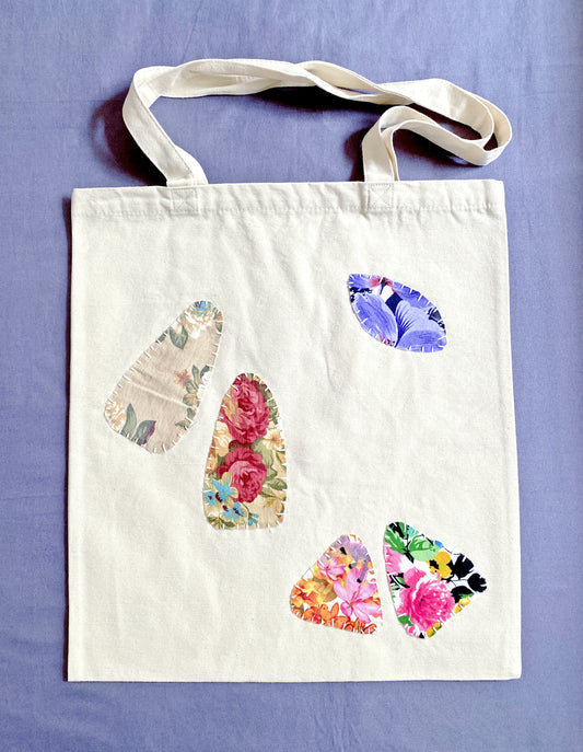 Neutral-toned canvas bag with artisan-style patchwork pattern