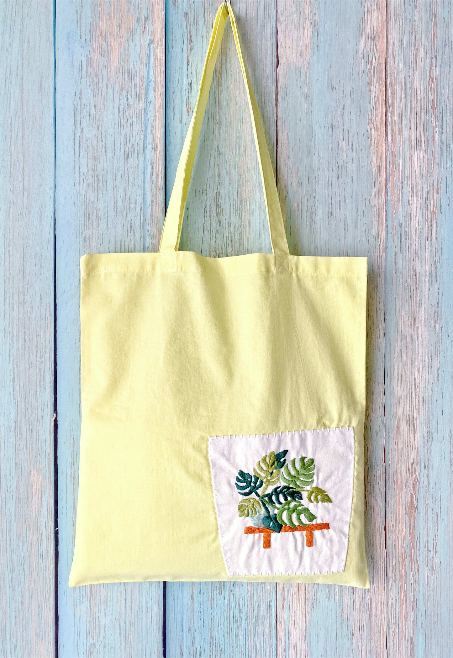 Sustainable cotton shoulder tote featuring a creative embroidered plant pot pattern, perfect for slow living style